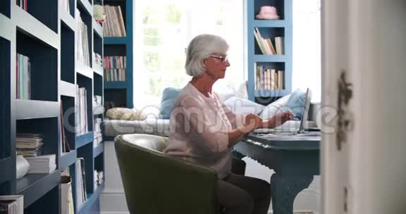 高级妇女在家庭办公室办公配有笔记本电脑视频的预览图