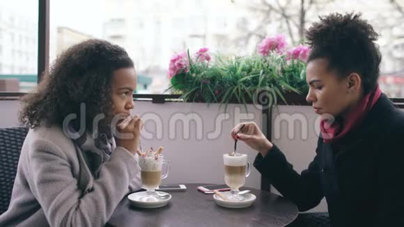两个迷人的混血女人在街头咖啡馆里聊天喝咖啡朋友参观商场后玩得开心视频的预览图