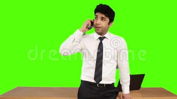 年轻商人在绿色背景下用手机说话视频的预览图