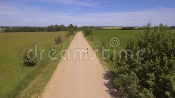 女孩在田野里的路上跑空中观景视频的预览图