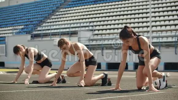 田径场的女跑运动员在比赛前蹲在起点在慢动作中视频的预览图
