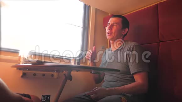男人坐在火车车厢里手里拿着铁路喝着咖啡和茶慢动作生活方式视频两个人视频的预览图