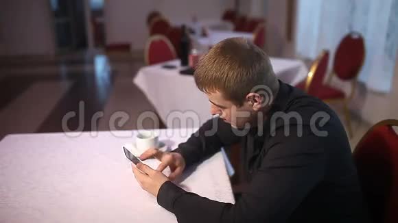 男人拿着智能手机上网坐在咖啡馆里视频的预览图