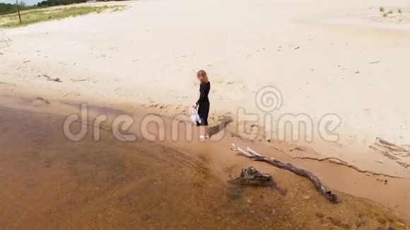 一个穿着连衣裙的年轻女子沿着海滩奔跑空中射击视频的预览图