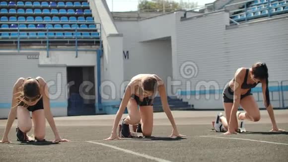 田径场的女跑运动员在比赛前蹲在起点在慢动作中视频的预览图