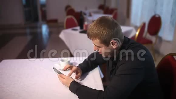 一个男人拿着智能手机在咖啡馆里上网视频的预览图