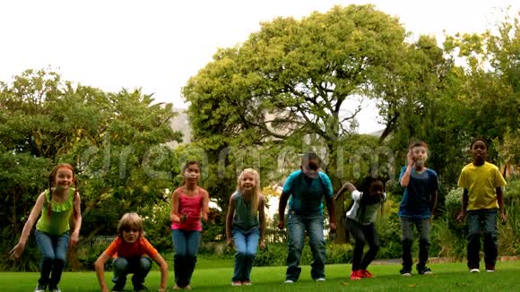 可爱的学生在校外的草地上跳跃视频的预览图