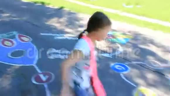 女孩在柏油路上的幼稚图画上奔跑视频的预览图