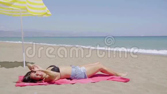 时髦的年轻女子在海滩上日光浴视频的预览图