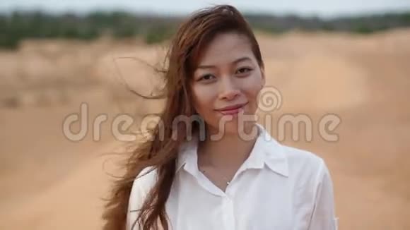 亚洲女人微笑户外沙漠风吹头发视频的预览图