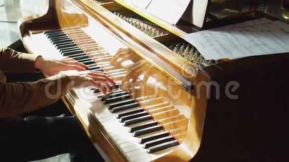弹钢琴那个年轻人弹钢琴这位美丽的钢琴家演奏旋律室内窗户发出悦耳的灯光视频的预览图