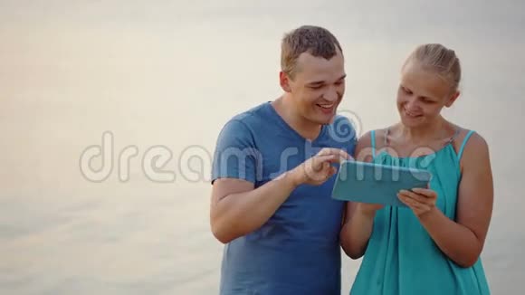 年轻夫妇在海边使用平板电脑视频的预览图