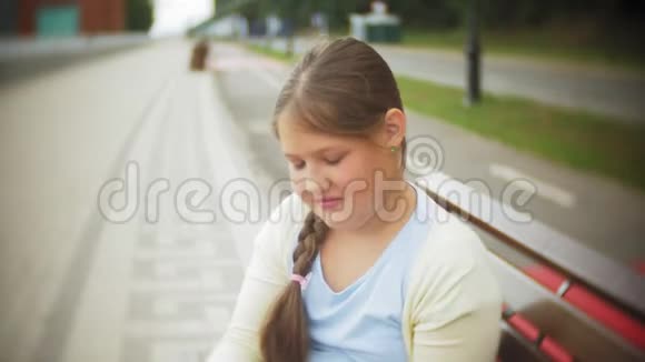 一个可爱的小女孩正在吃蛋糕双手坐在公园的长凳上这是一个概念视频的预览图