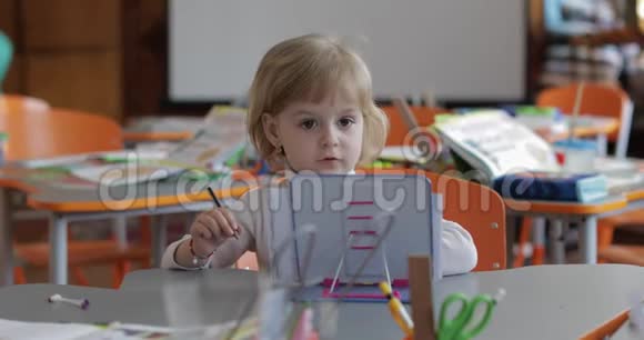 女孩在教室的桌子上画画教育坐在书桌前的孩子视频的预览图