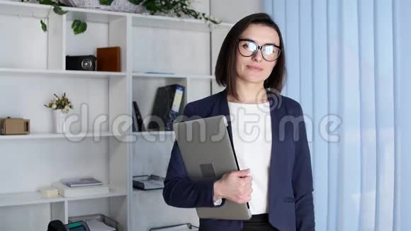 商务女性拿着笔记本电脑看着相机视频的预览图