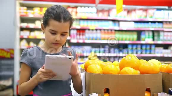 带着平板电脑在超市买橘子的女孩视频的预览图