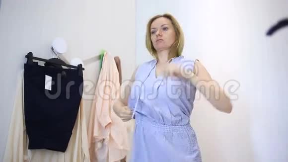 女人在服装店购物挑选衣服女人在更衣室试穿衣服照镜子视频的预览图