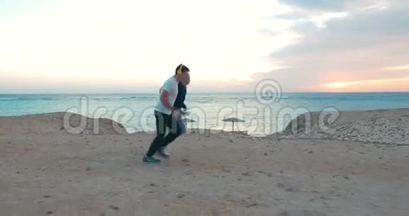 日落时分年轻人在海滩上慢跑视频的预览图