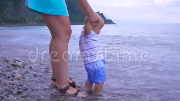 妈妈带着一个小孩沿着海滩散步视频的预览图