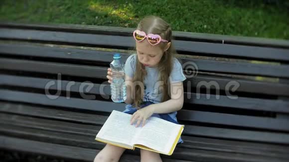 一个年轻女孩坐在城市的木凳上看书背景是一个城市公园视频的预览图