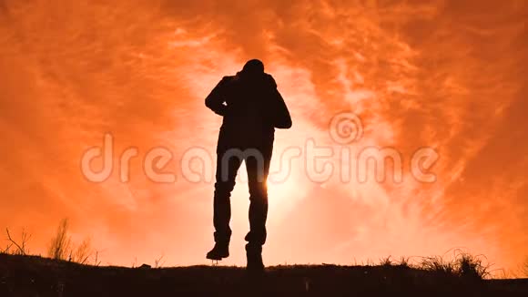 剪影游客徒步旅行者带着背包从山顶欣赏日落景色徒步旅行者的剪影视频的预览图