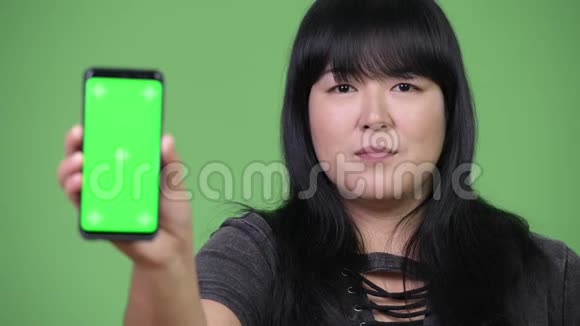 快乐超重的亚洲女人展示电话视频的预览图