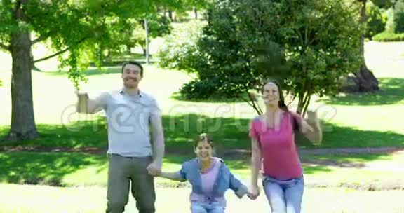 快乐的父母和女儿在公园里跳跃视频的预览图