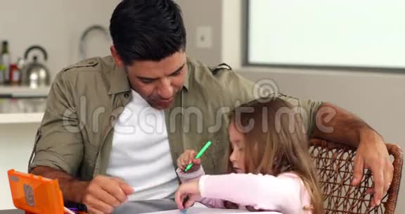 小女孩和她父亲一起在厨房的桌子旁画画视频的预览图