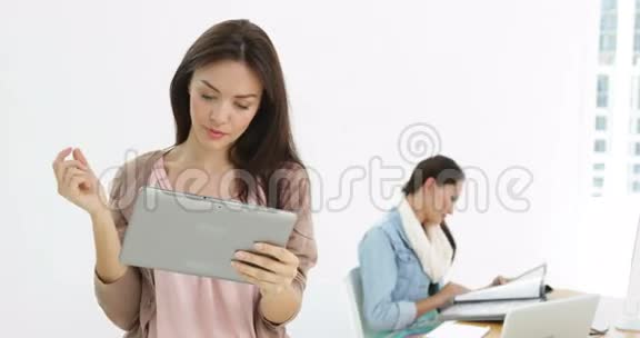 创意女商人使用平板电脑的同事在她身后视频的预览图