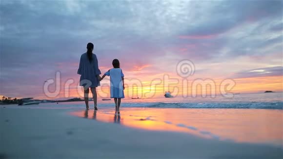 小女孩和爸爸在海滩日落时的剪影视频的预览图