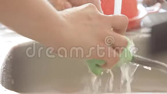 女人在水流下洗厨具视频的预览图