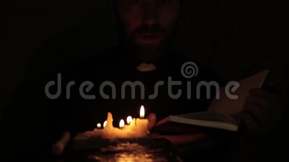 牧师在黑暗中点燃蜡烛阅读圣经视频的预览图