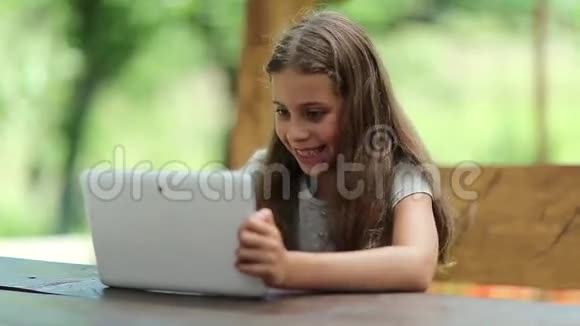 有平板电脑的漂亮女孩坐在避暑别墅的长椅上视频的预览图