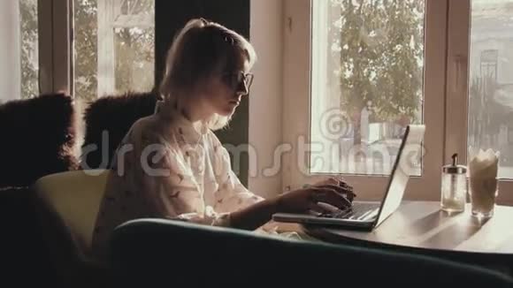快乐的年轻美女在咖啡馆里用笔记本电脑工作视频的预览图
