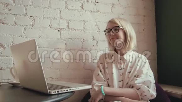 快乐的年轻美女在咖啡馆里用笔记本电脑工作视频的预览图