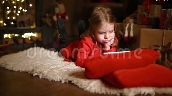 小女孩躺在地毯上拿着礼物在桌上视频的预览图