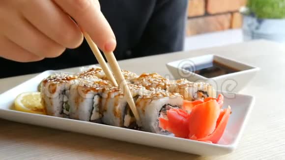 一个十几岁的男孩拿着中国竹签的寿司卷把它放进酱油里拿一块粉红色的生姜视频的预览图