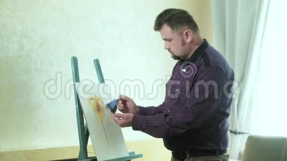 画架上的男画家在蝴蝶旁边画一朵花视频的预览图