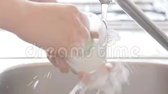 女人在水流下洗厨具视频的预览图