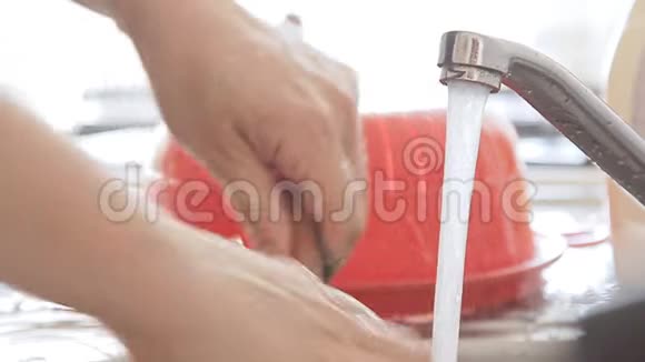 女人在水流下清洗厨房用具视频的预览图