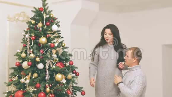 年轻夫妇在新年装饰和礼物和圣诞树上相爱视频里有噪音视频的预览图