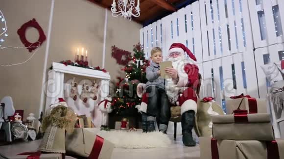 圣诞老人和小男孩选择餐桌上的礼物视频的预览图