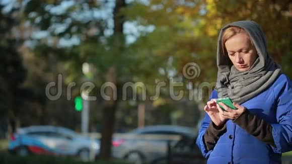 秋公园里一个微笑的年轻女子在打电话视频的预览图