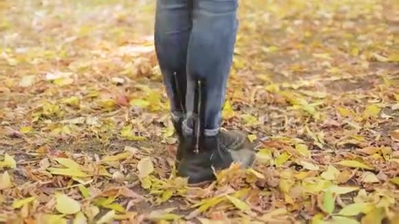 女人走在橙色叶子上的秋天公园里跟踪射击低角度视频的预览图