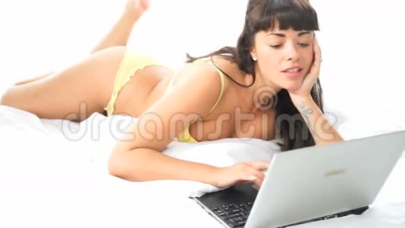 黑发女人带着笔记本电脑躺在床上视频的预览图