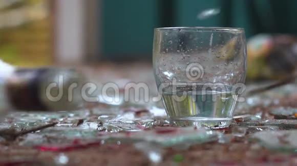 在碎玻璃的背景下将伏特加倒入玻璃杯中视频的预览图