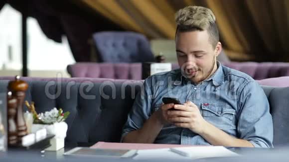 男人坐在餐厅里用手机发短信微笑着视频的预览图