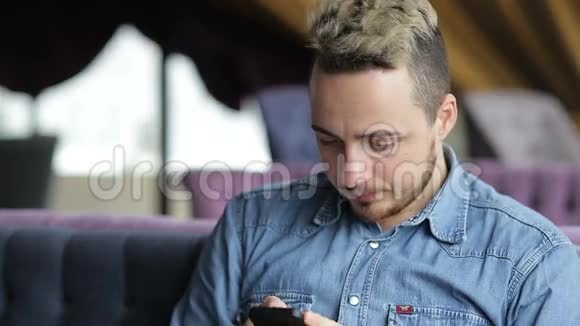 男人坐在餐厅里用手机发短信微笑着视频的预览图