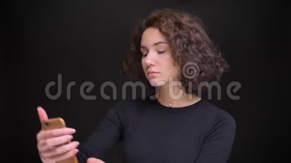 年轻有魅力的白种人女性在手机上自拍的特写照片背景是黑色的视频的预览图