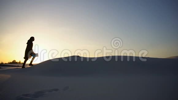 傍晚日落时分男性穆斯林在沙漠中的白沙上登上沙丘之巅视频的预览图